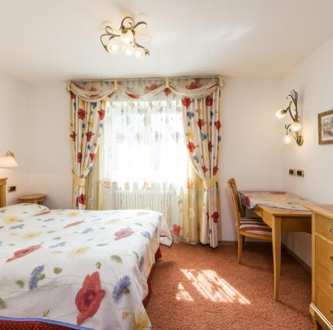 A bedroom with a double bed, desk, and TV of the Poppy Suite