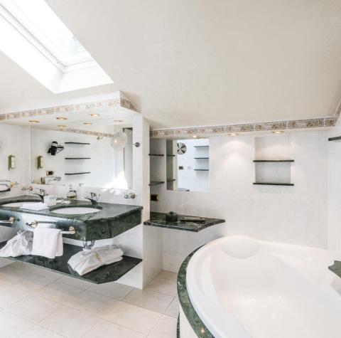 Marble bathroom with two washbasins, shower, and washtub of the Poppy Suite